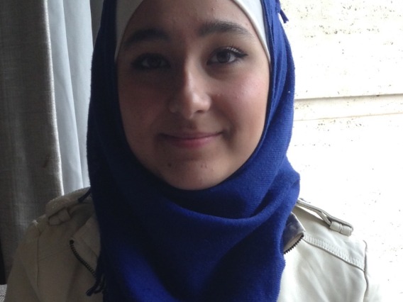 Mumina, a woman in blue hijab smiling