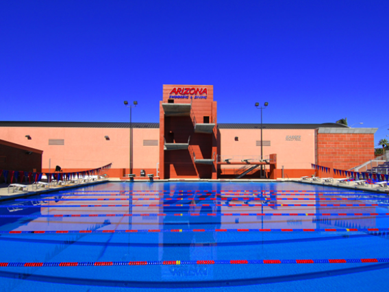an outdoor swimming pool in front of a building with UArizona branding