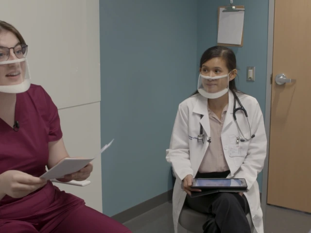 Image of two young healthcare professionals speaking to an young man with a disability.