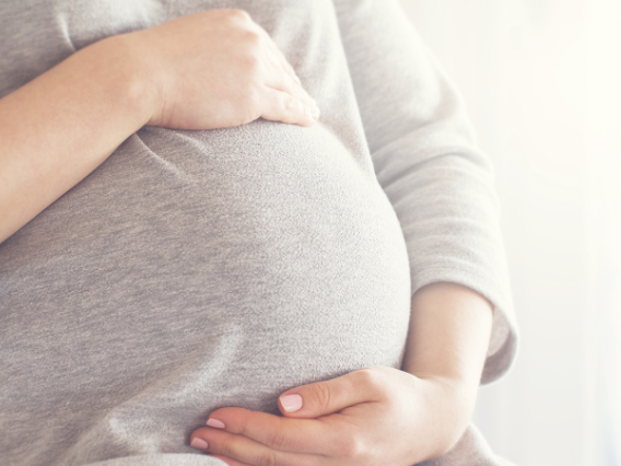 Close-up image of pregnant woman holding her stomach with both hands