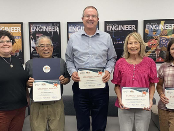 Five people standing in a row, each holding a certificate in front of them.