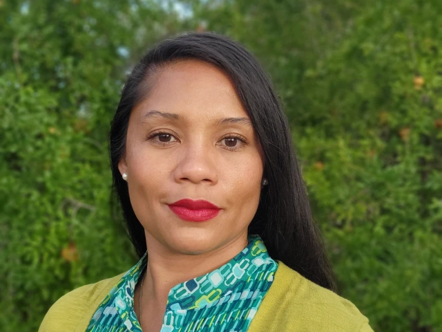 Jacy, a smiling Black-Filipina woman with dark long hair in green top and yellow cardigan