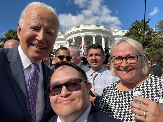 President Joe Biden (left), Gabe Martinez (Center) and Sallie Martinez (Right), all wearing formal attire, on a clear day with the White House in the background