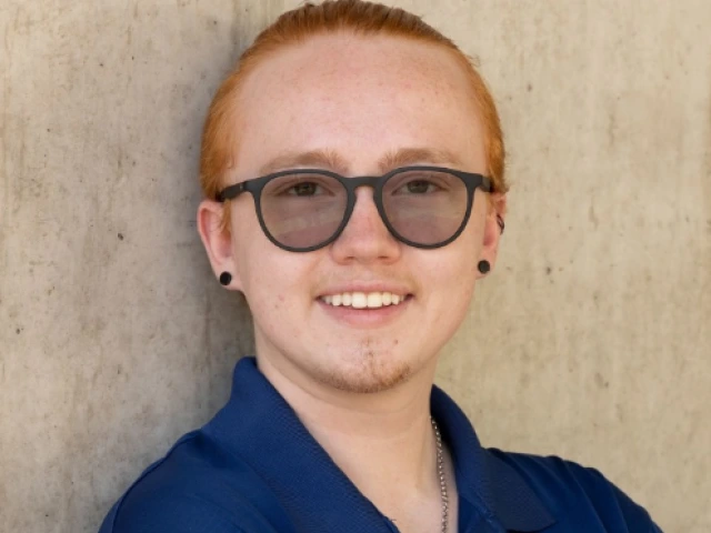 Austin Randall, author of this article. A white person with short red hair wearing glasses and a blue collared shirt.