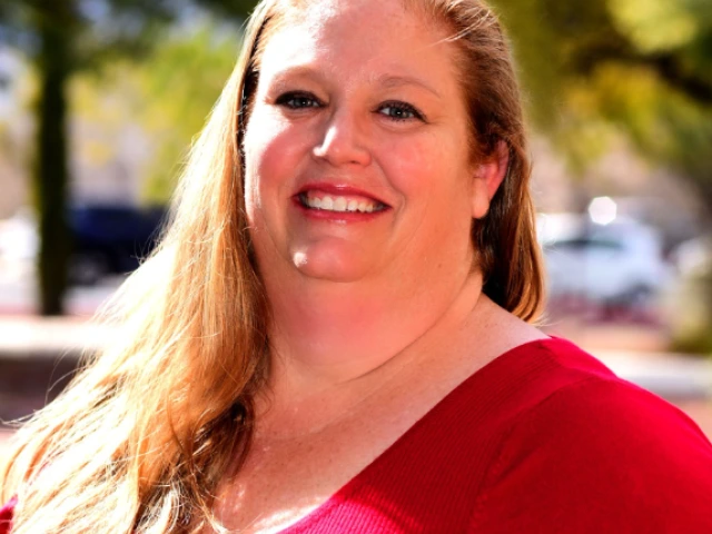 Danielle Hallahan, a white woman, standing outside wearing a red shirt