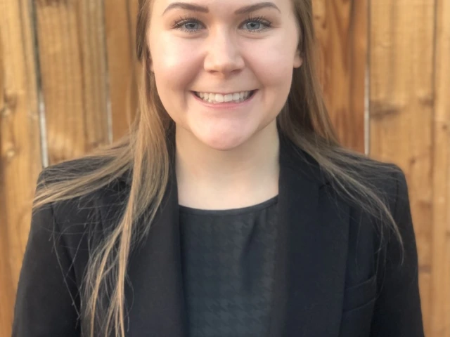 Alyssa Gandolph, a white woman with brown hair wearing a black blazer and gray blouse