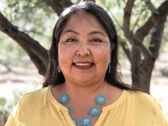 Native woman with long dark hair wearing a yellow blouse and turquoise necklace