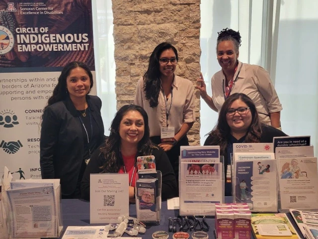 Sonoran Center staff Jacy Farkas, Celina Urquidez, Kelsey Montano, Lisa Ayo, and Jessica Rojas Franco behind a table with informational brochures about the Sonoran Center programs.