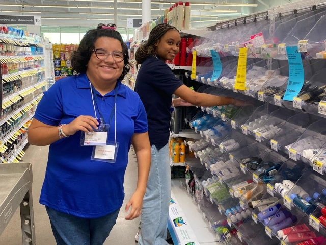 Two employee participants stocking store shelves and smiling