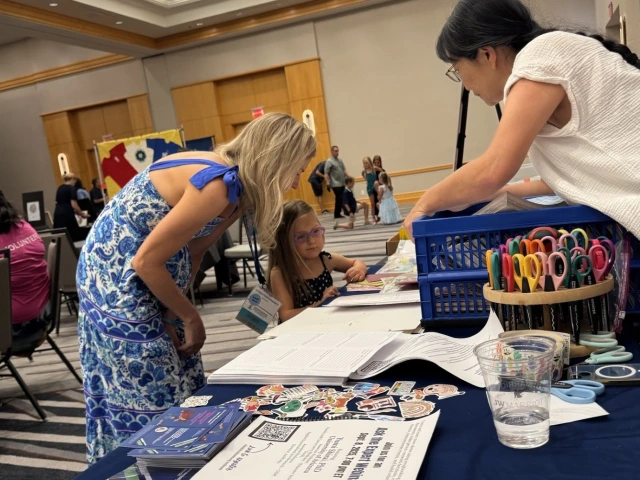 Dr. Yumi Shirai shows a young girl and her mother how to create a scrapbook page