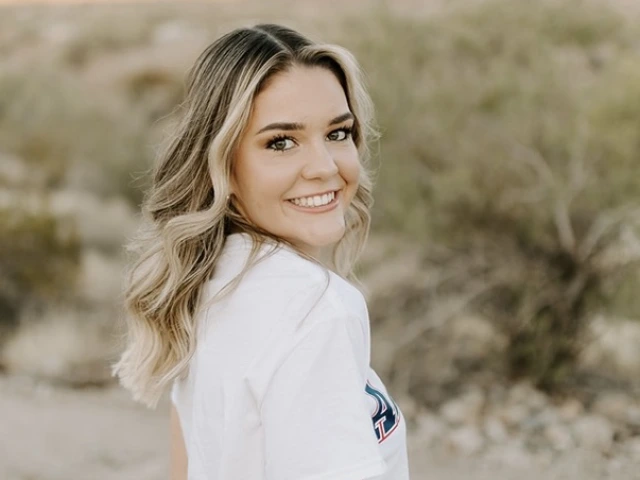 young woman wearing a white t-shirt, has medium length hair and standing in front of a desert background