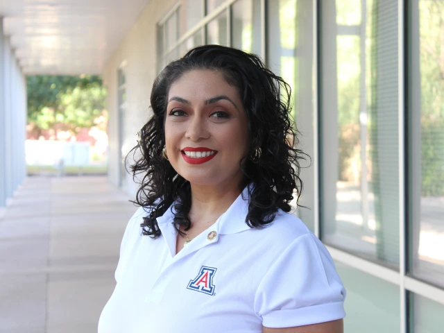Headshot of woman wearing a white U of A shirt, has short hair and is smiling at the camera