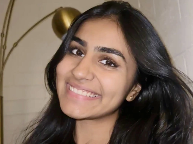 Srishti Rajeev in Blue Shirt against white wall, she is smiling at the camera