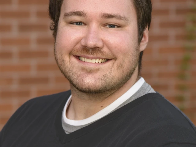 Patrick Rivers, a white man with short dark hair smiling and wearing a dark grey sweater