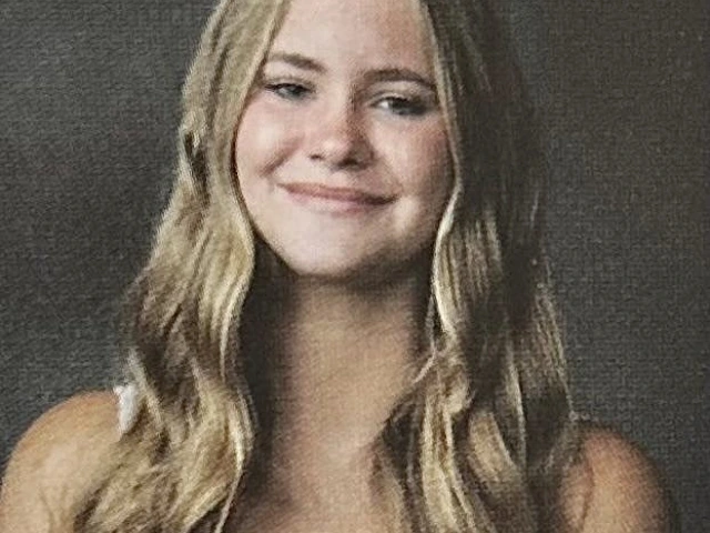 white woman with long blonde hair, wearing a white top. 