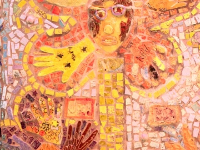 Photo of a mural that resembles a flower with a face at the center and hands for petals.