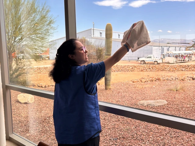 A WBLP participant smiles as she cleans the windows at the Pima Air and Space Museum