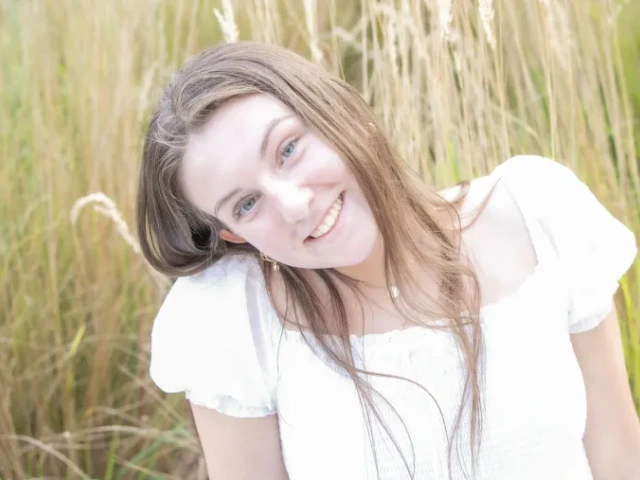 Sophia Westphal, a young person with long hair wearing a flowing white top, smiling in a field