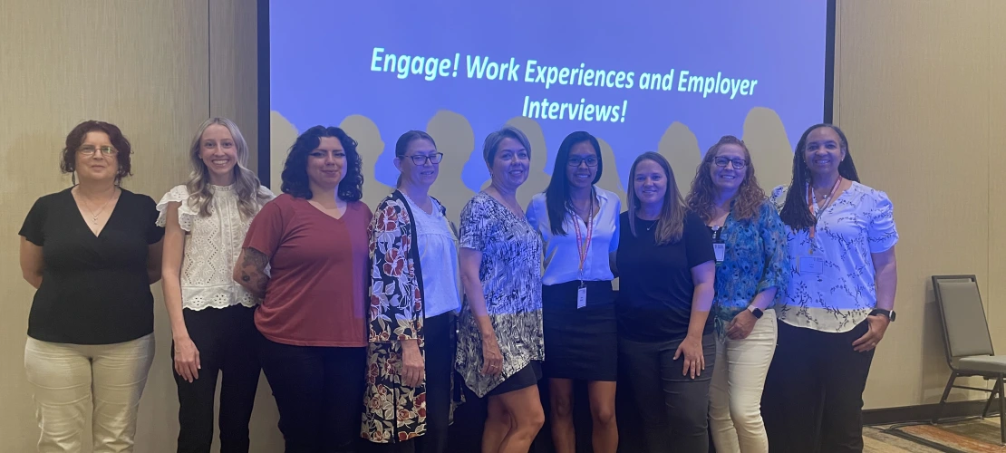 A group of staff standing in front of a projector screen.