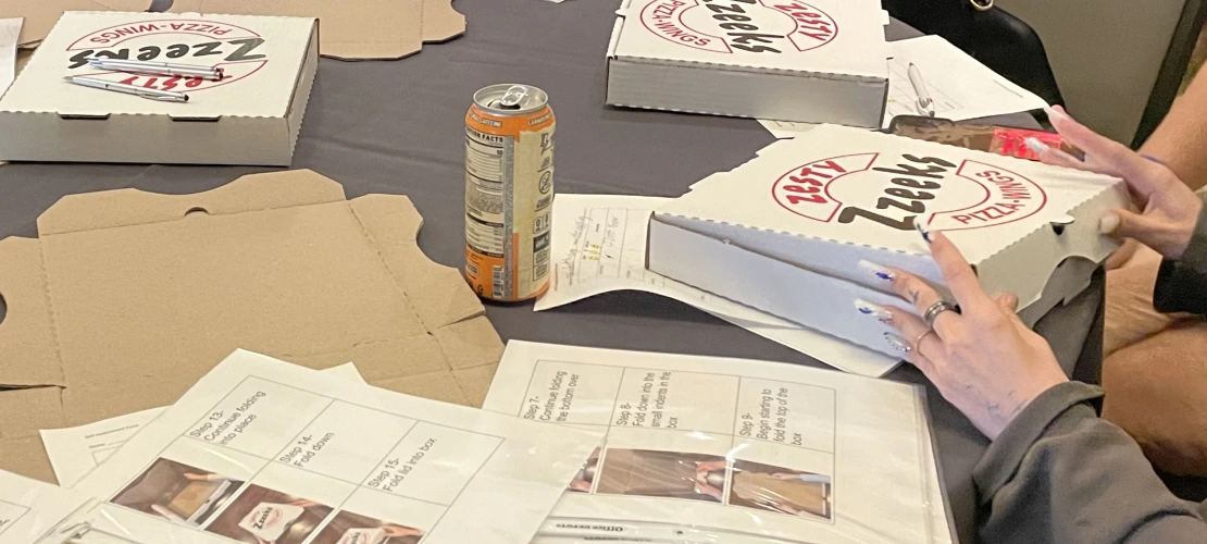 Close-up of hands folding a pizza box.