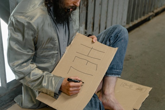 A Homeless man writing HELP sign