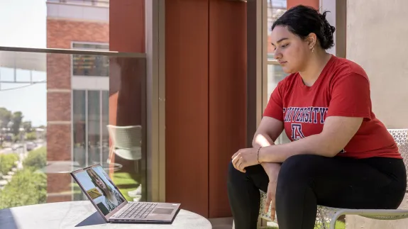 A woman wearing red UA top sitting next to a laptop