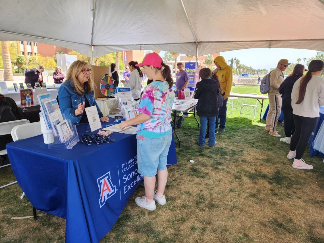 An attendee at Neurodiversity Day talks with Lupita Loftus at the Sonoran Center exhibit booth