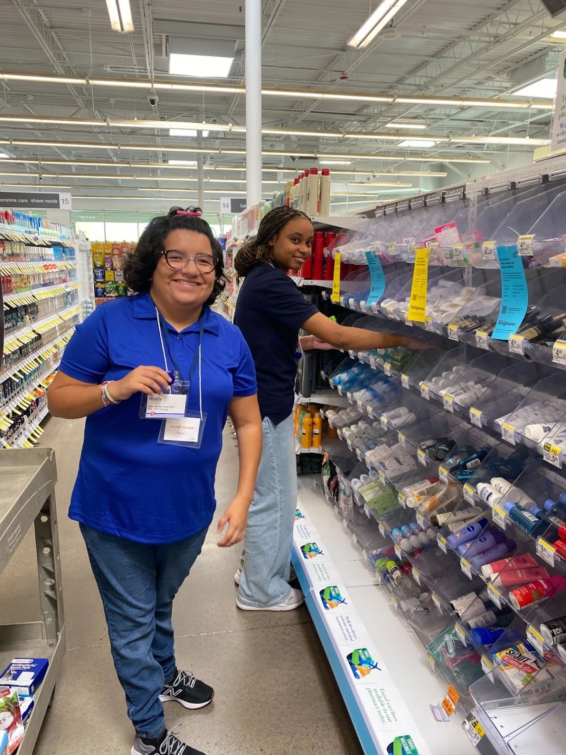 Two employee participants stocking store shelves and smiling