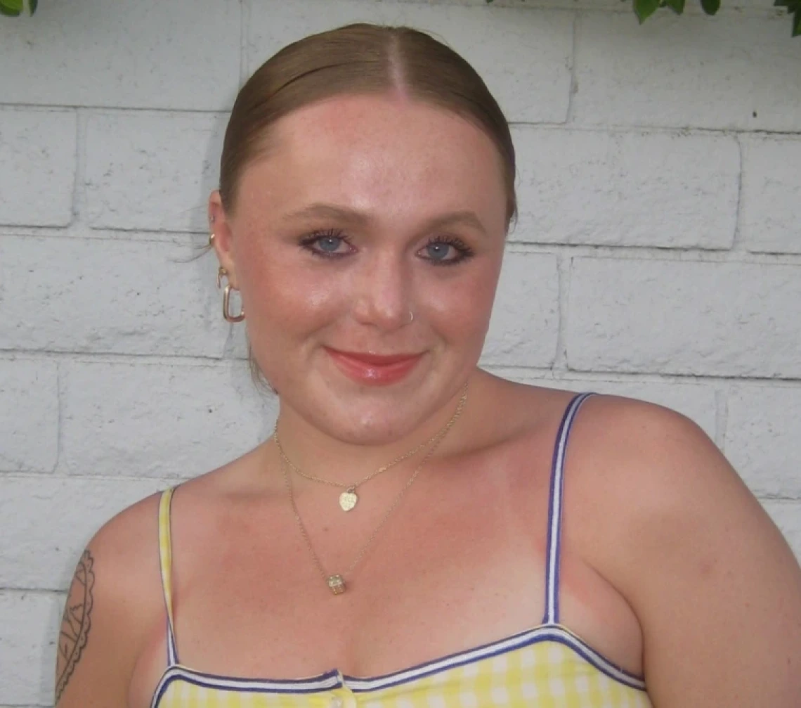 Kendall Smith, a young person with fair skin and light brown hair in a yellow top, smiling