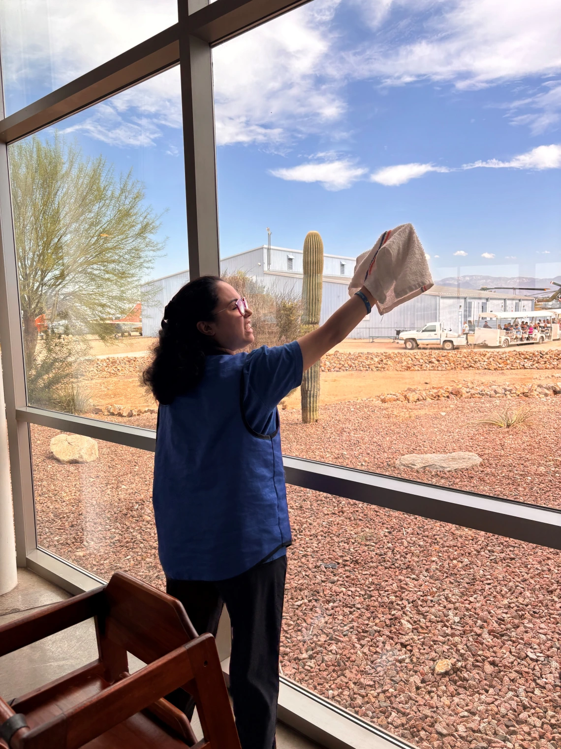 A WBLP participant smiles as she cleans the windows at the Pima Air and Space Museum