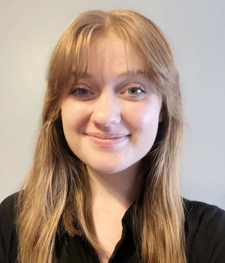Headshot of Kate Larsen, a white woman with strawberry blonde hair and green eyes.