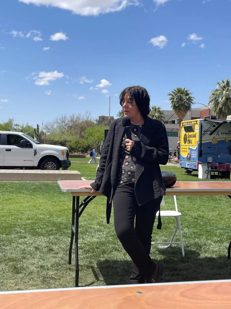Gondy Leroy holding a microphone and speaking while leaning on a table.