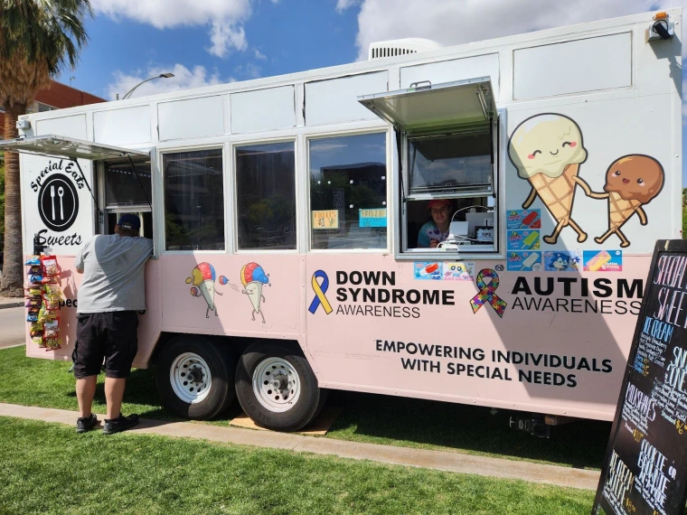 A Special Eats food truck. The truck is pink with a cartoon illustration of anthropomorphized ice cream, as well as graphics for Down Syndrome and Autism awareness