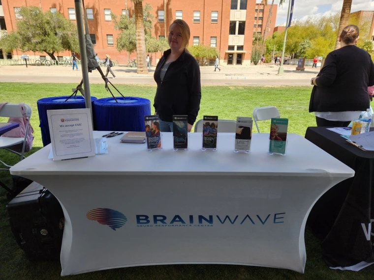 BrainWave representative standing behind the BrainWave table. The table has a selection of brochures.