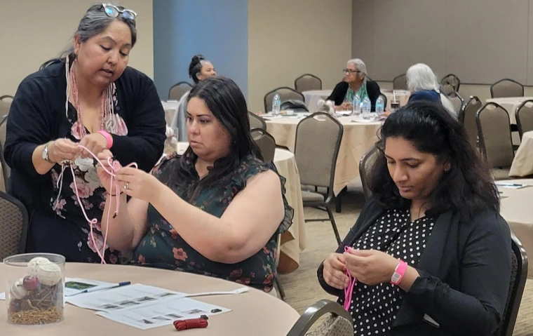 Agnes Attakai helps attendees make rope. 
