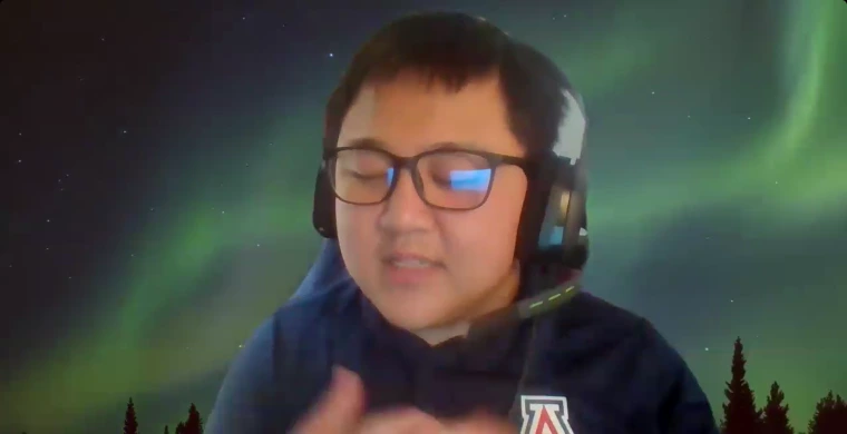 Isaac Zwinger-Nathanson presents on self-advocacy skills. He is wearing headphones and a U of A shirt, speaking in front of a background with the Northern Lights