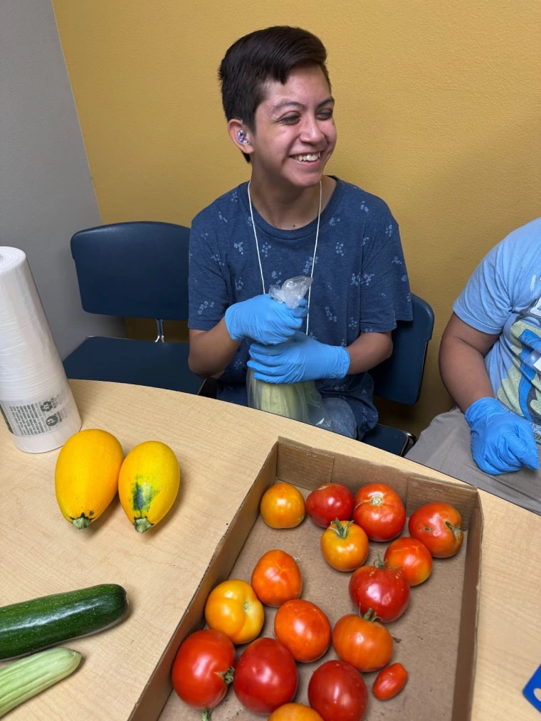 An employee participant smiles while handling vegetables