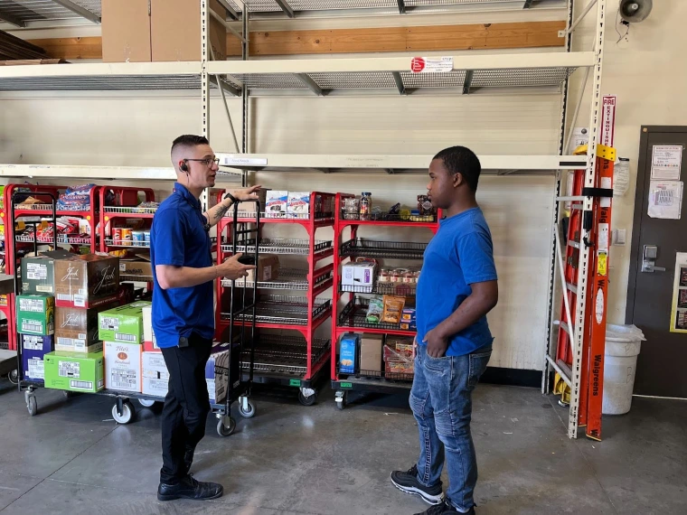 Two workers talking in the back room of a grocery store.