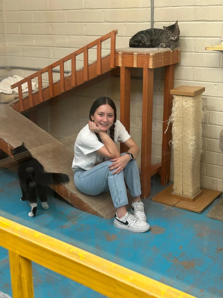 An employee participant smiles next to several cats.