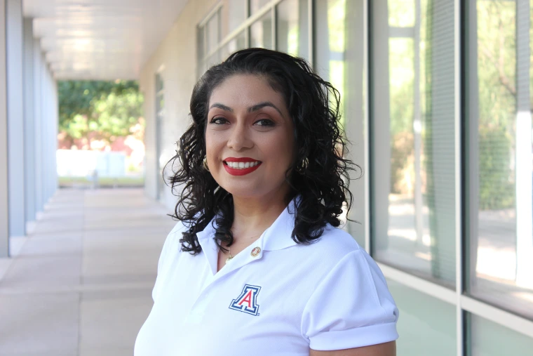 Headshot of woman wearing a white U of A shirt, has short hair and is smiling at the camera
