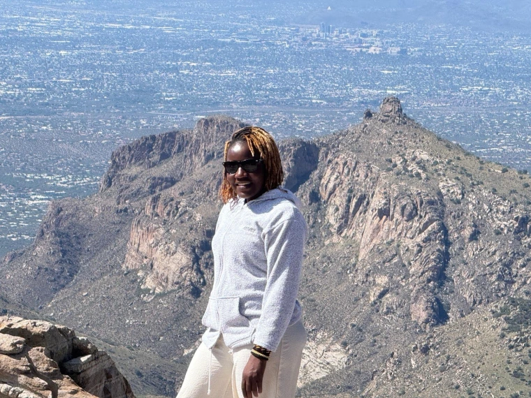Mai poses for a photo at the top of a cliff on Mount Lemmon overlooking a wide view of the Tucson valley
