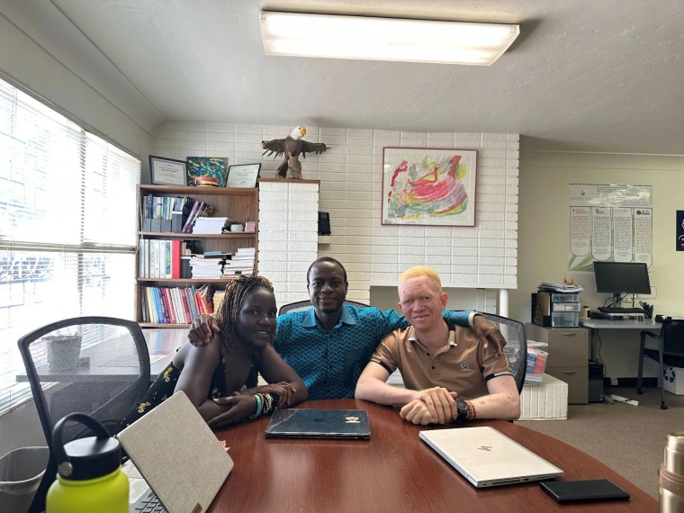 Mai and Kelvin sitting in a sunlit office at a table with Mohammed Naabo