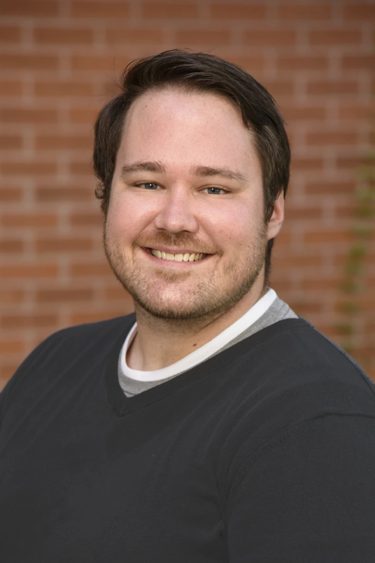 Patrick Rivers, a white man with short dark hair smiling and wearing a dark grey sweater