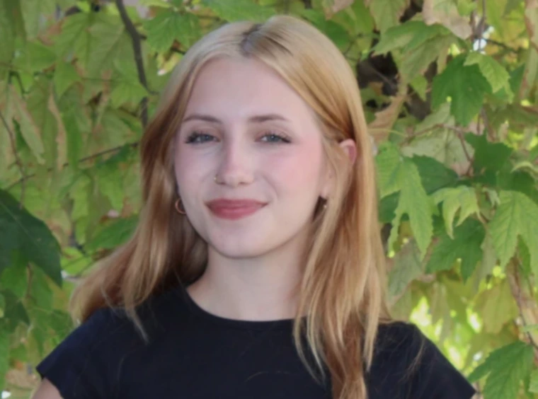 young woman wearing a black shirt and have blonde/brunette hair, she is smiling at the camera