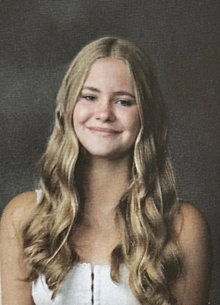 white woman with long blonde hair, wearing a white top. 