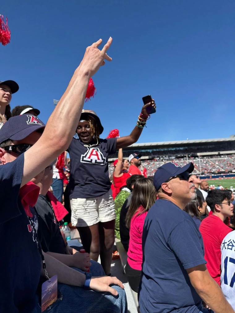 Mai stands and celebrates with the fans after a touchdown at the U of A Wildcats game.