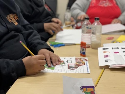 Participants are writing on their worksheet with a yellow number 2 pencil while using magazine cuts added to their paper.