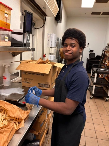 An employee participant handling food and smiling